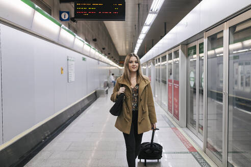 Frau mit Gepäck auf Rädern in einer U-Bahn-Station - JRVF02665