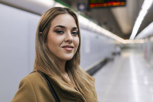 Lächelnde junge Frau in der U-Bahn-Station - JRVF02666