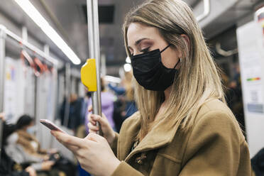 Passenger with protective face mask using smart phone in train - JRVF02667