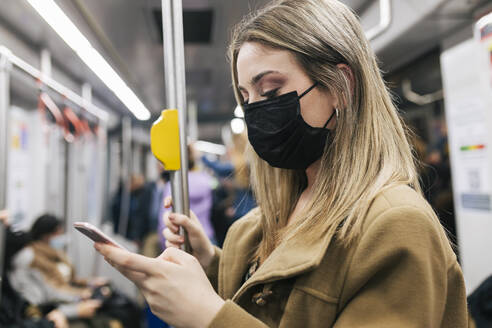 Passenger with protective face mask using smart phone in train - JRVF02667