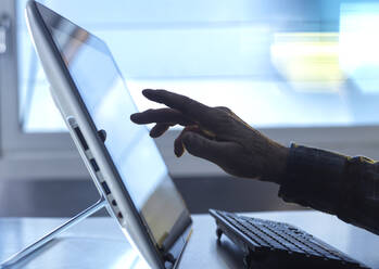 Hand eines Technikers, der im Home Office einen Tablet-PC mit Tastatur benutzt - ABRF00948