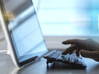 Die Hand eines Ingenieurs tippt auf der Tastatur eines Tablet-PCs am Schreibtisch im Heimbüro - ABRF00952