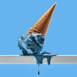 Appetitlich geschmolzenes blaues Eis mit Waffeltüte auf weißem Geländer gegen hellen wolkenlosen Himmel platziert - ADSF33415