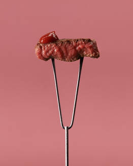 Peace of appetitlich blutiges Steak mit Ketchup auf Edelstahl Fleisch Tranchiergabel gegen rosa Hintergrund - ADSF33422