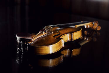 Studioaufnahme einer liegenden Geige vor schwarzem Hintergrund - DAWF02439