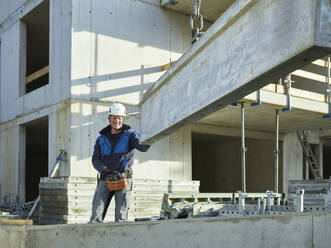 Lächelnder Arbeiter in der Nähe von Baumaterial auf der Baustelle - CVF01810