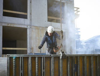 Worker holding chain attached with construction material at site - CVF01814