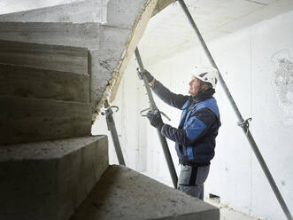 Worker unscrewing support poles by stairs at construction site - CVF01817