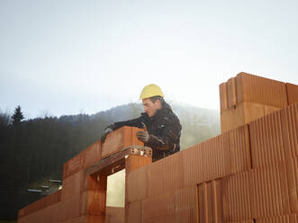 Bauarbeiter beim Befestigen von Ziegeln auf einer Baustelle - CVF01827