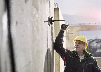 Arbeiter mit Hammer beim Lösen einer Eisenstange an einer Betonwand - CVF01828