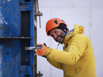 Arbeiter mit Schutzhelm, der eine Metallstruktur auf einer Baustelle untersucht - CVF01838