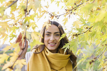 Schöne junge Frau durch gelbe Herbstblätter im Park gesehen - EIF03146