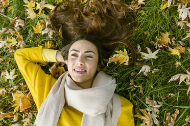 Young woman lying on grass in autumn park - EIF03157