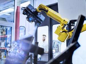 Engineer looking at surveying robot with 3D scan at factory - CVF01847