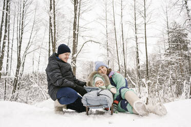 Vater und Mutter mit Tochter genießen den Schnee im Winterwald - EYAF01873