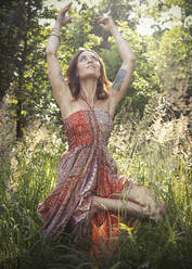 Frau übt Yoga inmitten von Pflanzen im Wald - JBYF00098