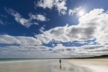 Australia, South Australia, Robe, Summer clouds over silhouette of female tourist walking alone along Fox Beach - FOF12724