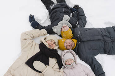Glückliche Familie, die zusammen im Schnee liegt - SEAF00399