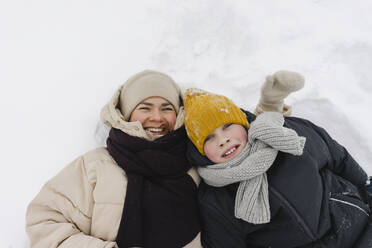 Lachende Mutter mit Sohn im Schnee liegend im Winter - SEAF00400