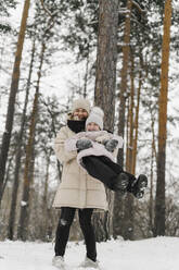 Fröhliche Mutter spielt mit Tochter im Winterwald - SEAF00410