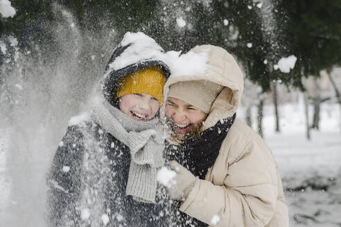 Fröhlicher Sohn und Mutter, die sich im Schnee vergnügen - SEAF00418