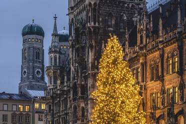 Deutschland, Bayern, München, leuchtender Weihnachtsbaum auf dem Marienplatz in der Abenddämmerung mit Mariendom und Rathaus im Hintergrund - KEBF02197