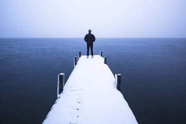 Tourist bewundert den See auf dem Steg stehend im Winter, Walchensee, Bayern, Deutschland - WFF00633