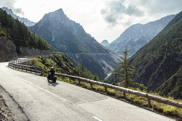 Biker riding motorcycle on road by Lechtal valley, Pfafflar, Tirol, Austria - WFF00637