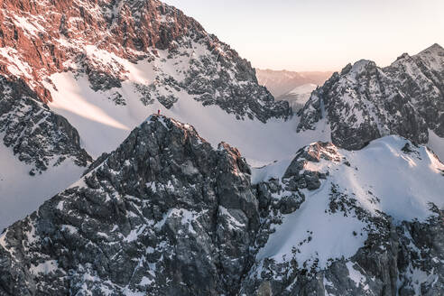 Abenteuerlustiger Mann, der bei Sonnenuntergang auf einem schneebedeckten Berg steht, Vorderer Tajakopf, Ehrwald, Tirol, Österreich - WFF00648