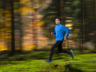 Engagierter junger Mann joggt im Wald - STSF03132