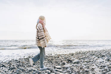 Teenage girl walking on stones at beach, Gagra, Abkhazia - OMIF00472