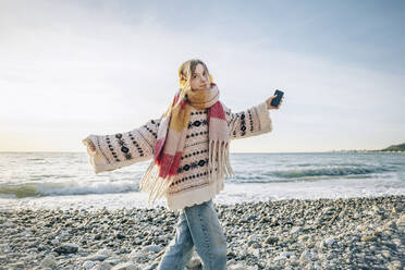 Carefree girl with headphones and smart phone enjoying vacation at beach, Gagra, Abkhazia - OMIF00476