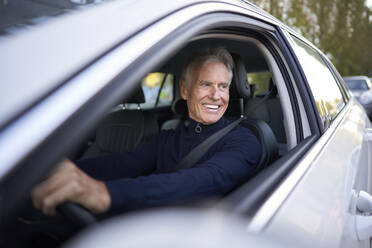 Lächelnder älterer Mann am Steuer eines Autos - PNEF02629