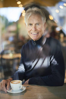 Lächelnder älterer Mann mit Kaffeetasse im Cafe - PNEF02636