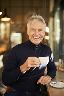 Lächelnder älterer Mann trinkt Kaffee in einem Cafe - PNEF02638