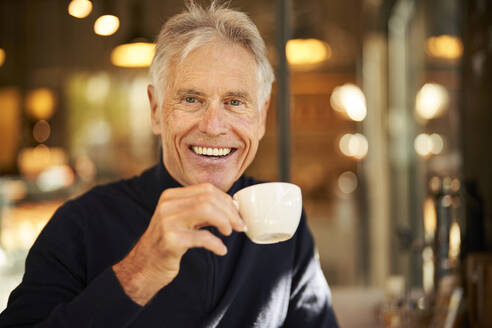 Älterer Mann mit Kaffeetasse im Cafe - PNEF02639