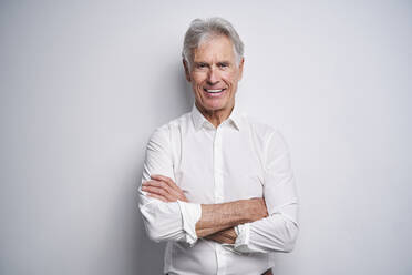 Confident businessman with arms crossed in front of white background - PNEF02656