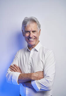 Happy elderly businessman with arms crossed in studio - PNEF02658