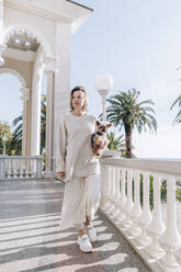 Blonde Frau mit Hund auf dem Balkon - OMIF00483