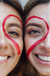Lächelnde Frauen mit roter Herzform im Gesicht - EGHF00351