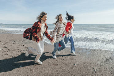 Unbekümmerte Freunde laufen am Strand an einem sonnigen Tag - OMIF00488