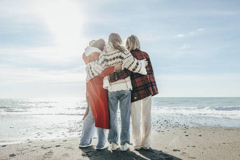 Freunde bewundern das Meer am Strand an einem sonnigen Tag - OMIF00492