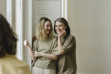 Happy mother and daughter in front of wall at home - SEAF00429