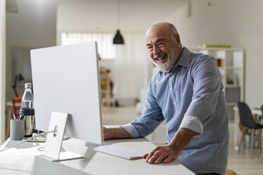 Cheerful senior freelancer with computer working from home - GIOF14768