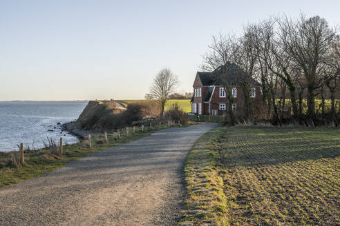 Deutschland, Schleswig-Holstein, Lübeck, Schotterweg zum abgelegenen Uferhaus in Travemünde - KEBF02216