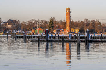 Deutschland, Schleswig-Holstein, Lübeck, Leeres Hafenbecken in der Abenddämmerung mit Leuchtturm im Hintergrund - KEBF02221