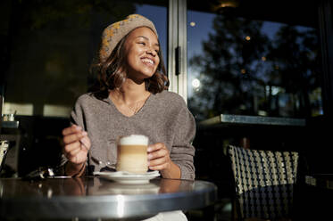 Junge Frau mit Kaffee lachend in einem Straßencafé - KIJF04373
