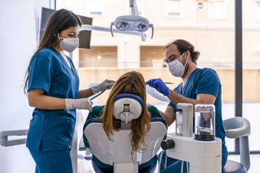 Doctor and nurse wearing protective face mask treating patient in medical clinic - DLTSF02649