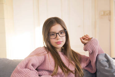 Vorpubertäres Mädchen mit Brille auf dem Sofa zu Hause - LVF09190