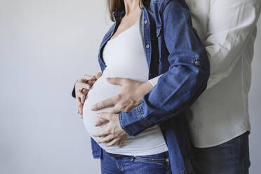 Man embracing pregnant woman by wall - EBBF05249